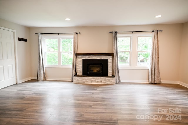 unfurnished living room with a stone fireplace, light wood-type flooring, and a healthy amount of sunlight