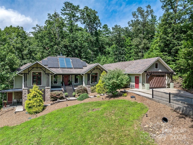 craftsman house with covered porch, solar panels, a garage, and a front lawn