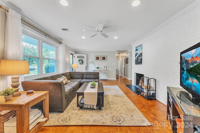 living room featuring light parquet floors, ceiling fan, ornamental molding, brick wall, and a brick fireplace