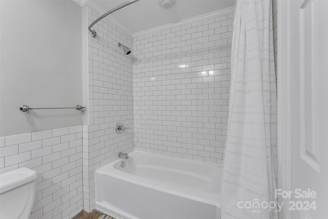 bathroom featuring tile walls, crown molding, toilet, and shower / bath combo with shower curtain