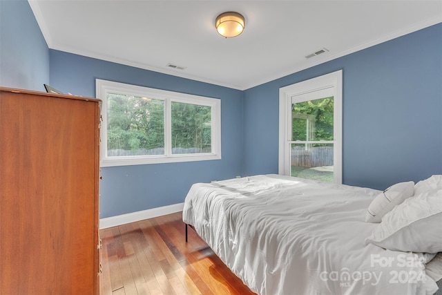 bedroom featuring multiple windows, ornamental molding, and light hardwood / wood-style flooring