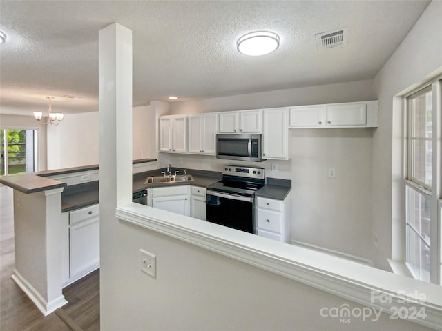 kitchen with appliances with stainless steel finishes, white cabinetry, sink, dark hardwood / wood-style flooring, and kitchen peninsula