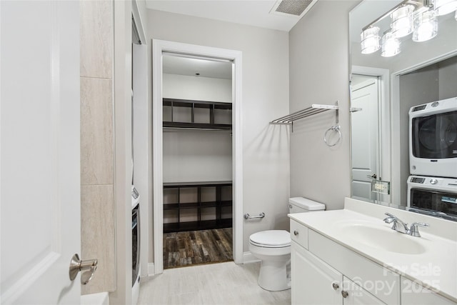 bathroom with vanity, toilet, and stacked washer / dryer