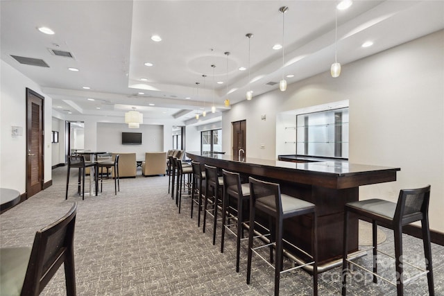 kitchen with carpet, decorative light fixtures, a kitchen breakfast bar, and a tray ceiling