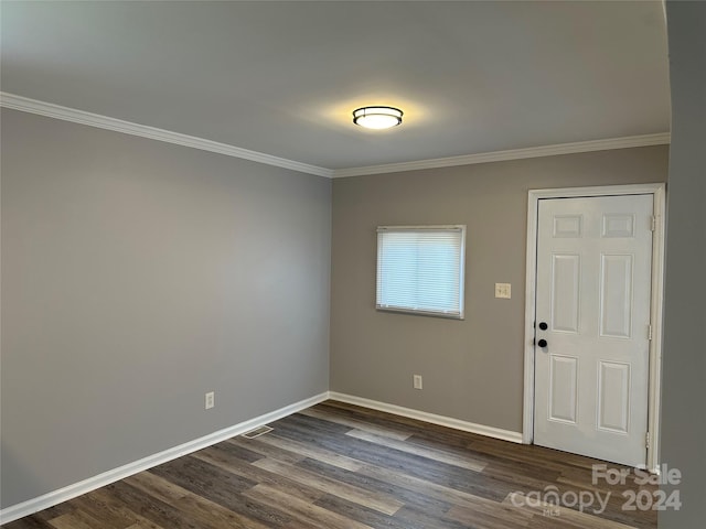 empty room featuring crown molding, visible vents, baseboards, and dark wood-type flooring