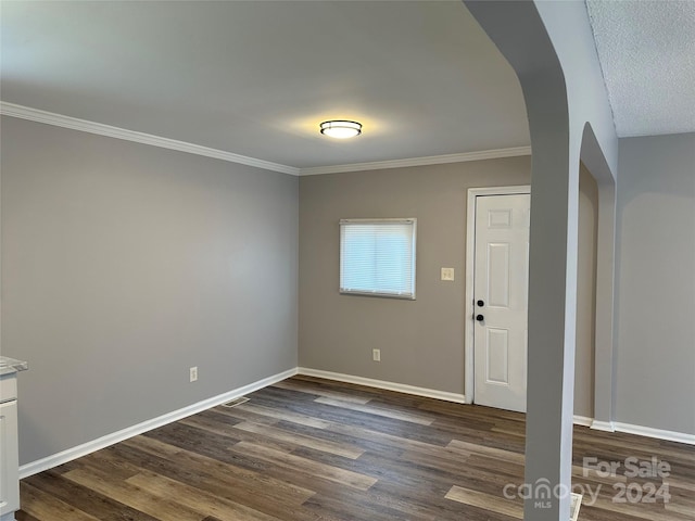 entryway with ornamental molding, dark wood-type flooring, arched walkways, and baseboards