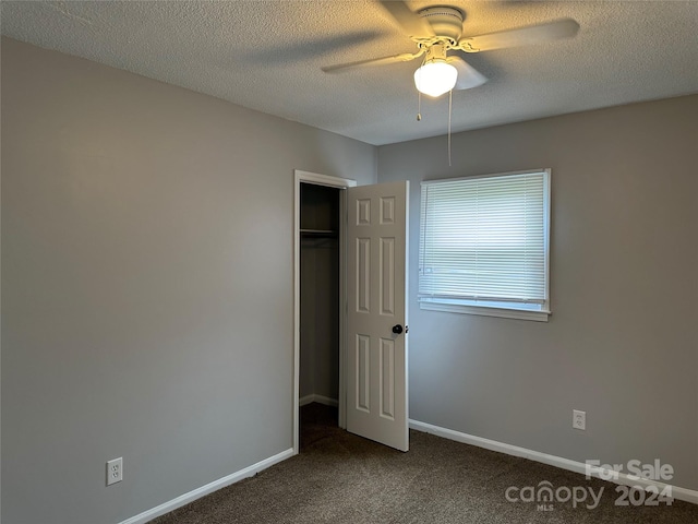 unfurnished bedroom featuring dark colored carpet, a textured ceiling, and baseboards