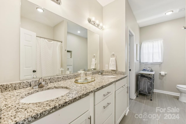 bathroom featuring dual vanity, toilet, and tile patterned floors