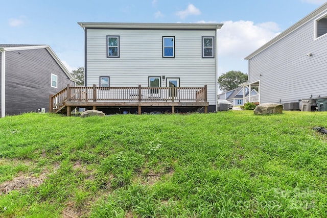 rear view of property featuring a deck, central AC unit, and a yard