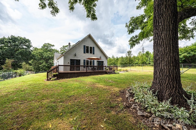 rear view of house with a wooden deck and a lawn