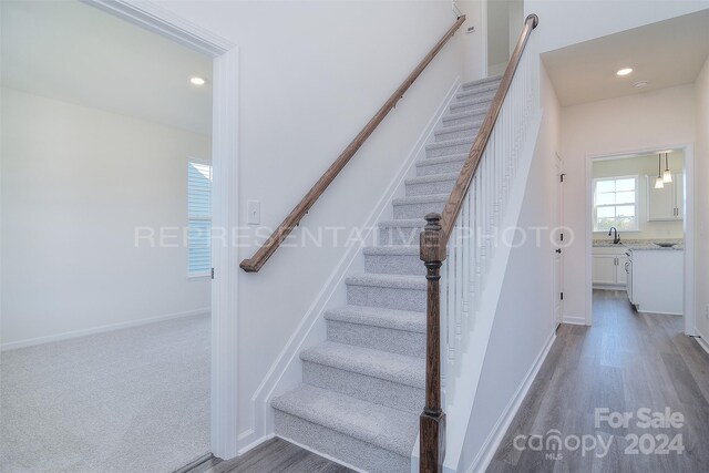 stairs featuring sink and dark hardwood / wood-style flooring