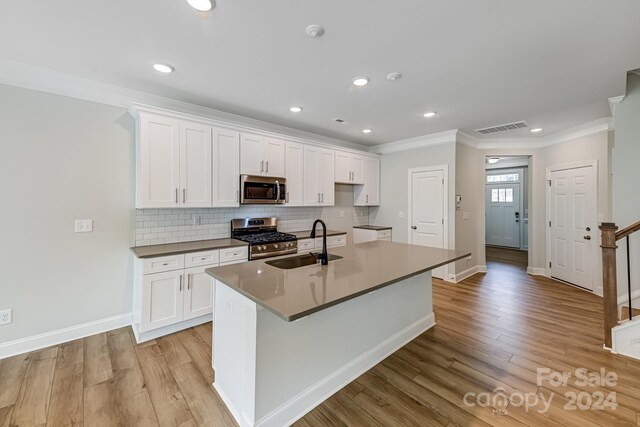 kitchen featuring a kitchen island with sink, light hardwood / wood-style floors, stainless steel appliances, sink, and white cabinets