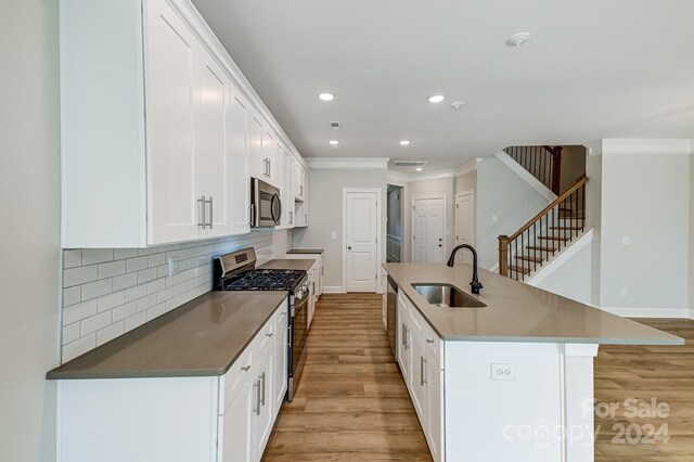 kitchen with stainless steel appliances, sink, a center island with sink, white cabinets, and light hardwood / wood-style floors