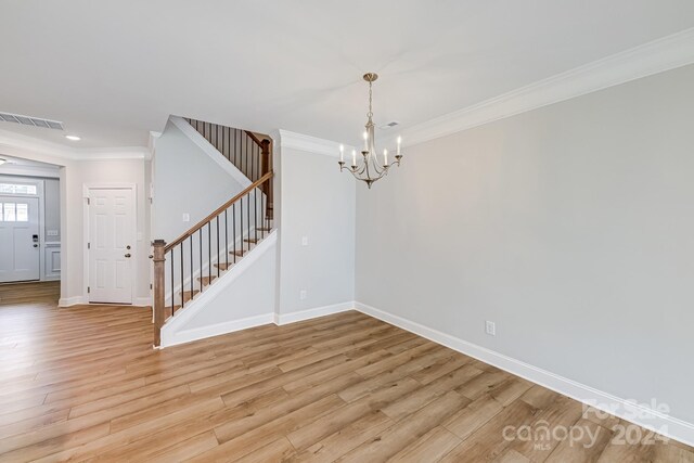 empty room featuring crown molding, light hardwood / wood-style flooring, and an inviting chandelier