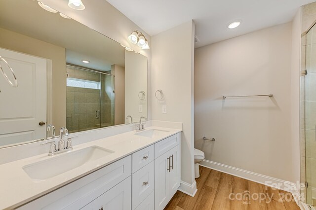 bathroom featuring a shower with shower door, toilet, vanity, and hardwood / wood-style flooring