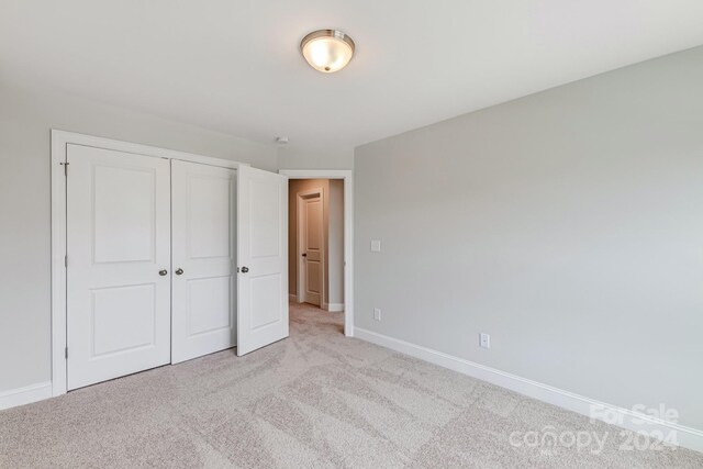 unfurnished bedroom with a closet and light colored carpet