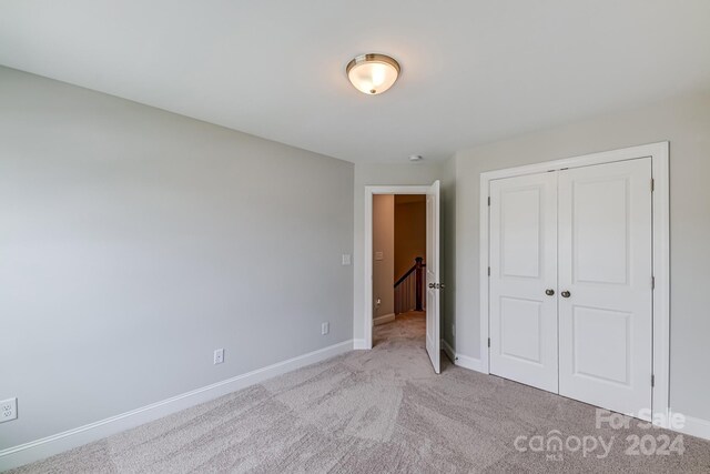 unfurnished bedroom featuring a closet and light carpet