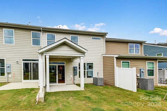 back of property featuring a lawn, cooling unit, and a patio