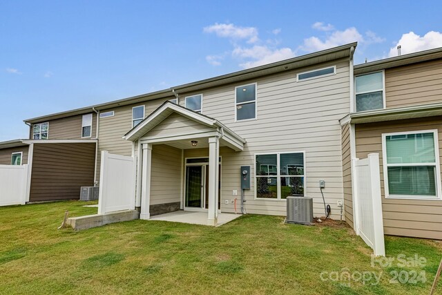 rear view of property with central AC and a lawn