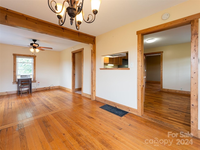 unfurnished living room featuring ceiling fan with notable chandelier and wood-type flooring