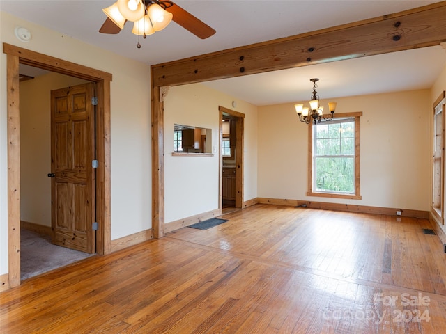 spare room with ceiling fan with notable chandelier and light hardwood / wood-style floors