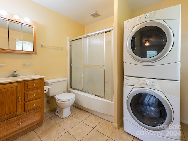 clothes washing area featuring light tile patterned floors, stacked washer and clothes dryer, and sink