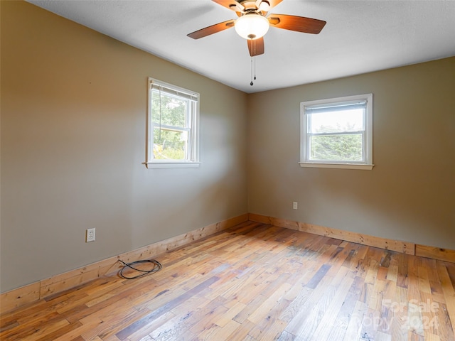 empty room with light hardwood / wood-style flooring, a wealth of natural light, and ceiling fan