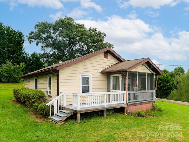 back of house featuring a sunroom and a lawn