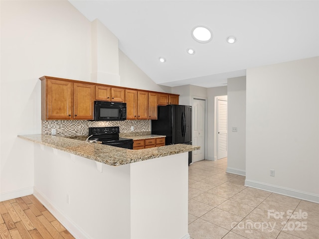 kitchen featuring backsplash, high vaulted ceiling, black appliances, light stone counters, and kitchen peninsula