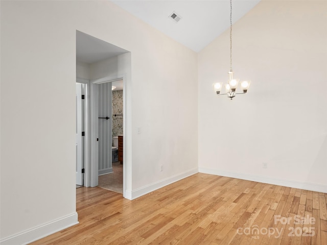 spare room featuring hardwood / wood-style flooring, lofted ceiling, and an inviting chandelier