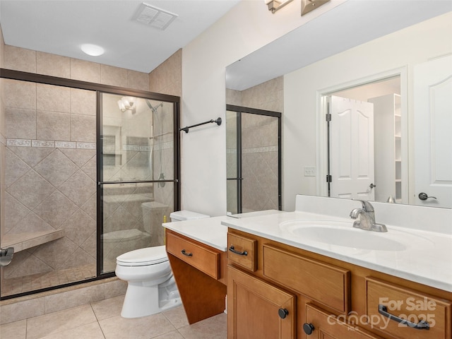 bathroom featuring tile patterned flooring, vanity, toilet, and a shower with door