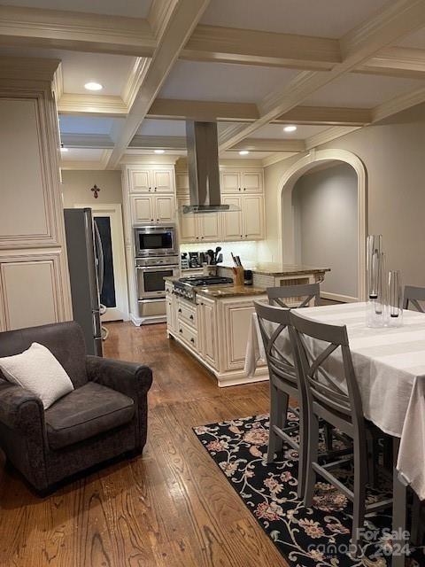 kitchen with beamed ceiling, stainless steel appliances, hardwood / wood-style floors, ventilation hood, and coffered ceiling