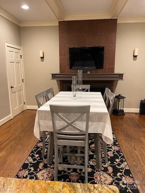 dining area with a fireplace, tile walls, crown molding, and hardwood / wood-style floors