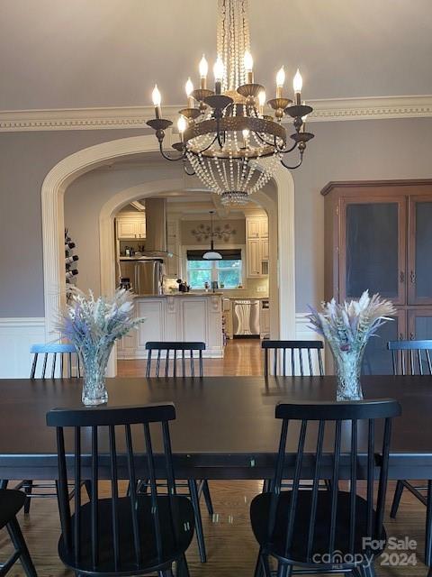 dining space with a notable chandelier, crown molding, and hardwood / wood-style floors