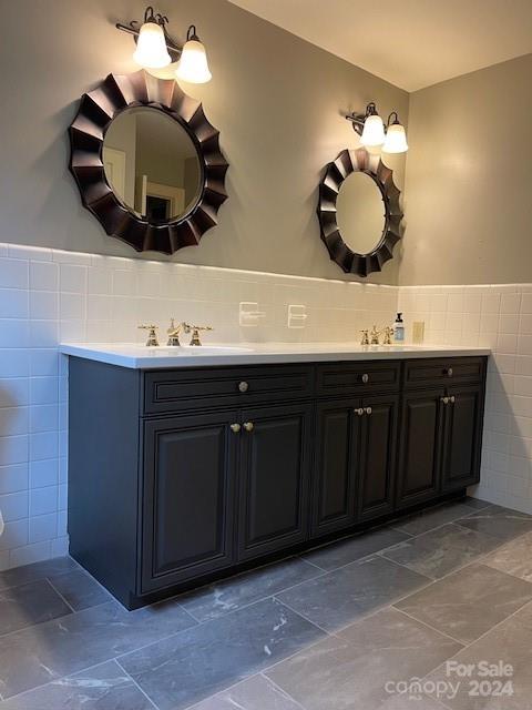 bathroom with tile walls, tile patterned floors, double sink vanity, and tasteful backsplash