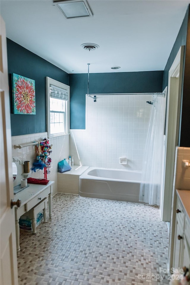 bathroom featuring vanity, shower / bath combo with shower curtain, tile walls, and tile patterned floors