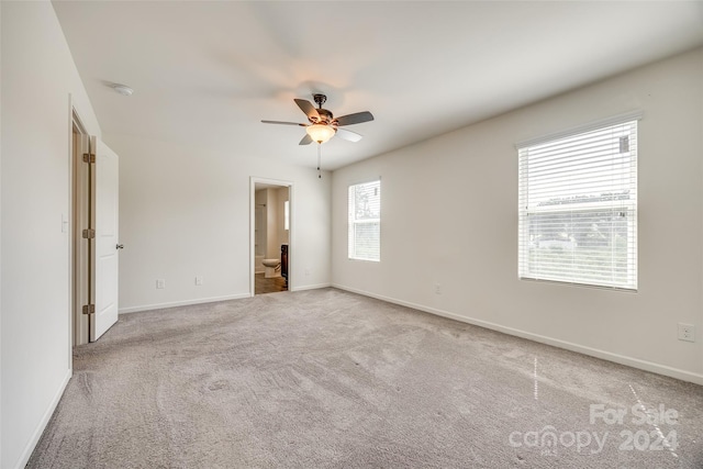 unfurnished bedroom with ceiling fan, connected bathroom, and light colored carpet