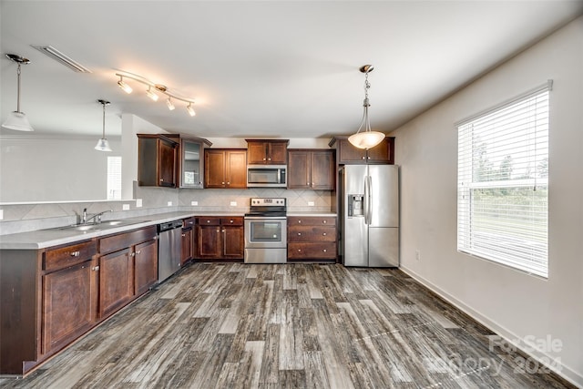 kitchen with sink, appliances with stainless steel finishes, dark hardwood / wood-style floors, pendant lighting, and backsplash