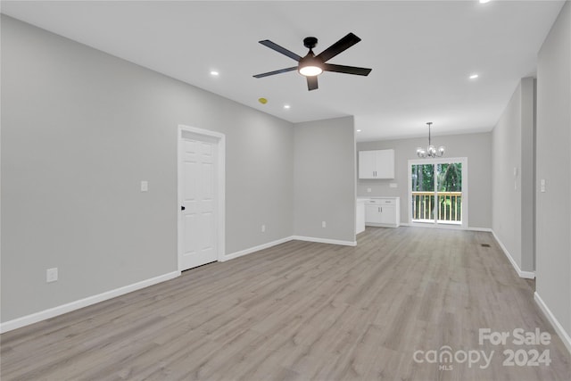 empty room featuring ceiling fan with notable chandelier and light hardwood / wood-style flooring