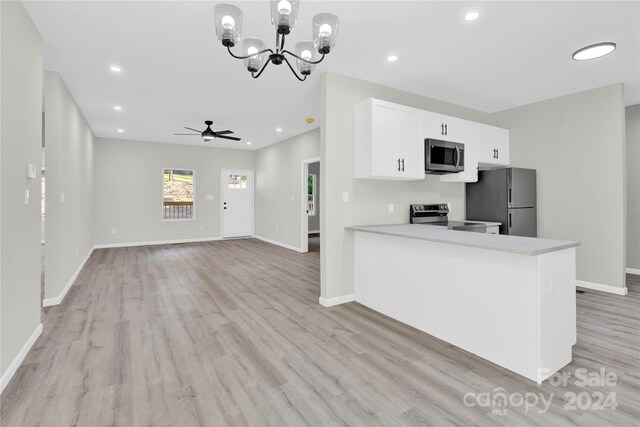 kitchen featuring light wood-type flooring, appliances with stainless steel finishes, ceiling fan with notable chandelier, white cabinetry, and kitchen peninsula