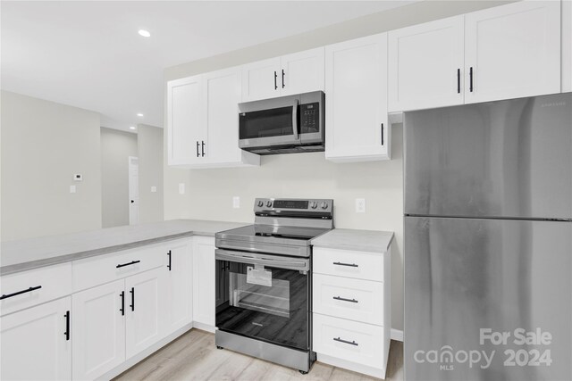 kitchen with stainless steel appliances, white cabinets, and light hardwood / wood-style flooring