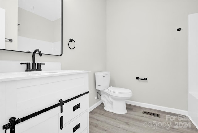 bathroom with toilet, hardwood / wood-style flooring, and vanity