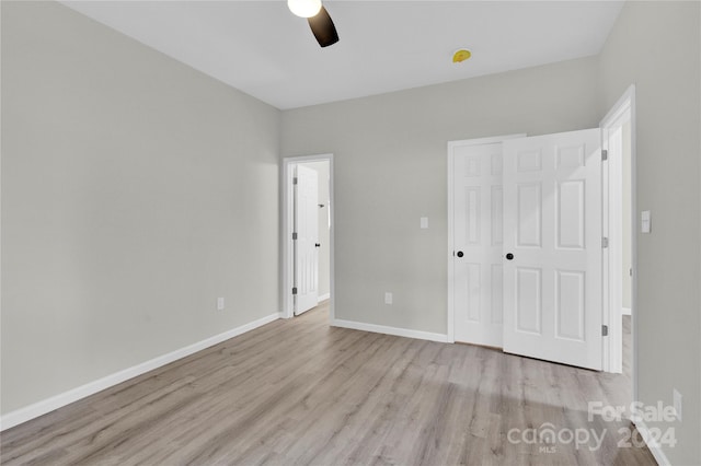 unfurnished bedroom with light hardwood / wood-style flooring, ceiling fan, and a closet