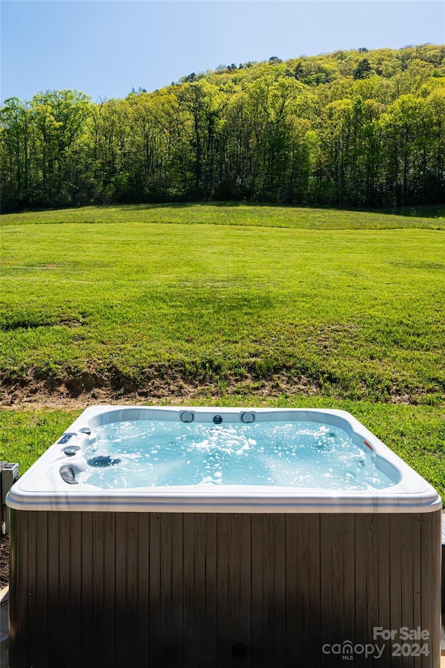 view of pool with a yard and a hot tub