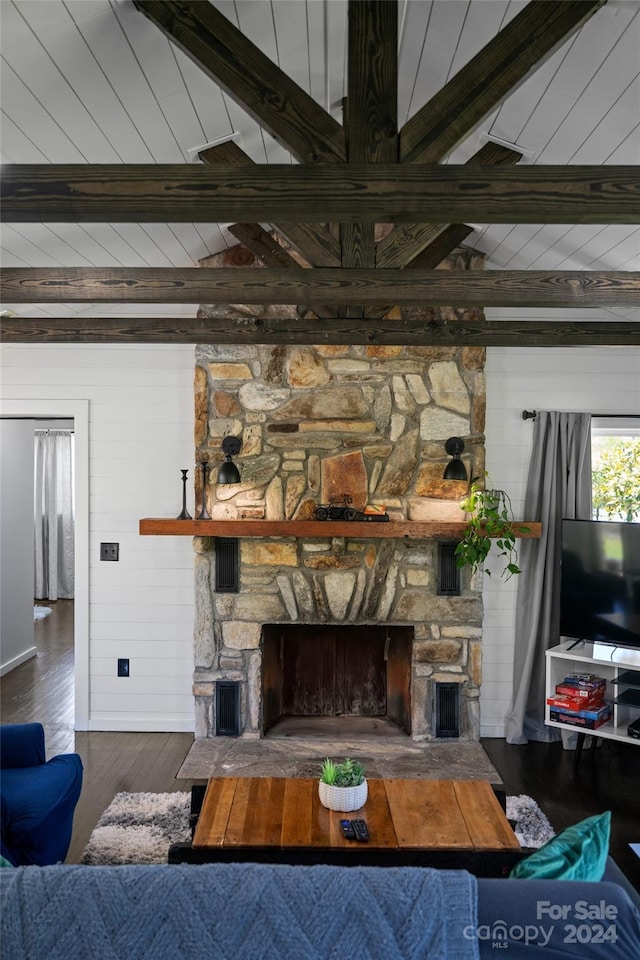 living room with a stone fireplace, dark hardwood / wood-style flooring, and lofted ceiling with beams