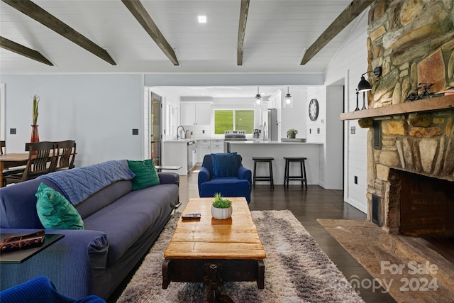 living room featuring lofted ceiling with beams, dark hardwood / wood-style floors, sink, and a fireplace