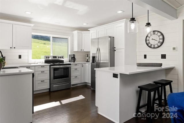 kitchen with a breakfast bar area, appliances with stainless steel finishes, white cabinetry, hanging light fixtures, and kitchen peninsula