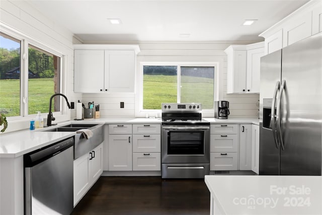 kitchen with sink, appliances with stainless steel finishes, backsplash, dark hardwood / wood-style floors, and white cabinets