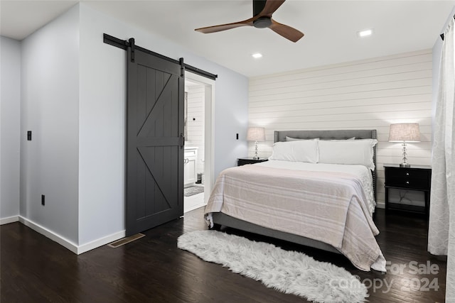 bedroom with a barn door, dark hardwood / wood-style floors, and ceiling fan