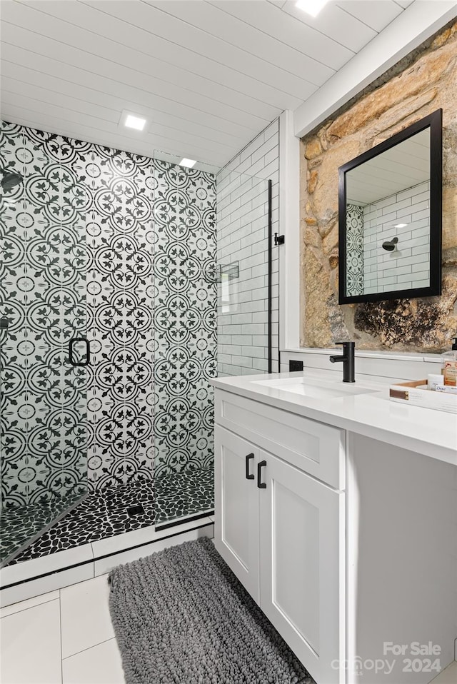 bathroom with tile patterned floors, vanity, and a tile shower